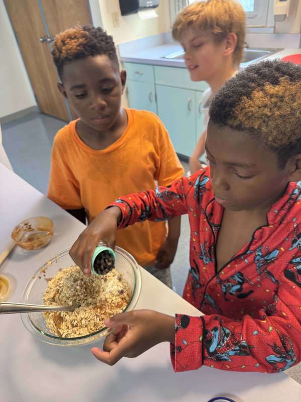 Three boys mixing ingredients in a bowl to make healthy cookies.
