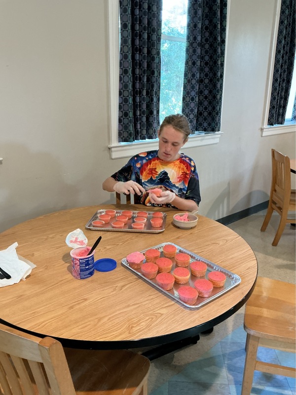 Boy spreading icing on a cupcake.