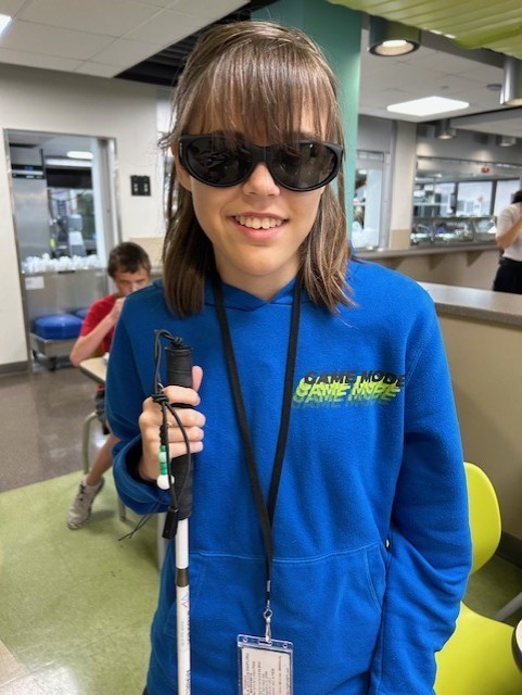 Girl wearing sunglasses and holding a cane.