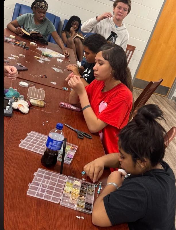 Girls making jewelry with beads.