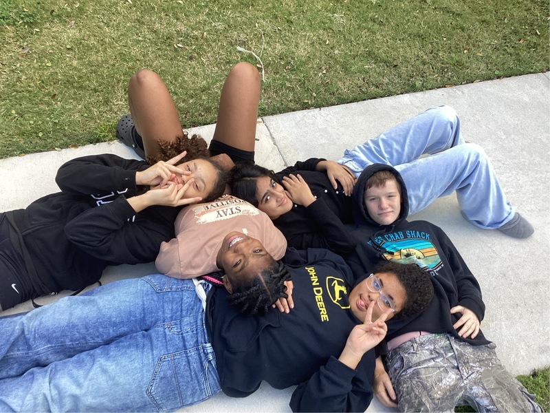 5 students laying on the sidewalk.