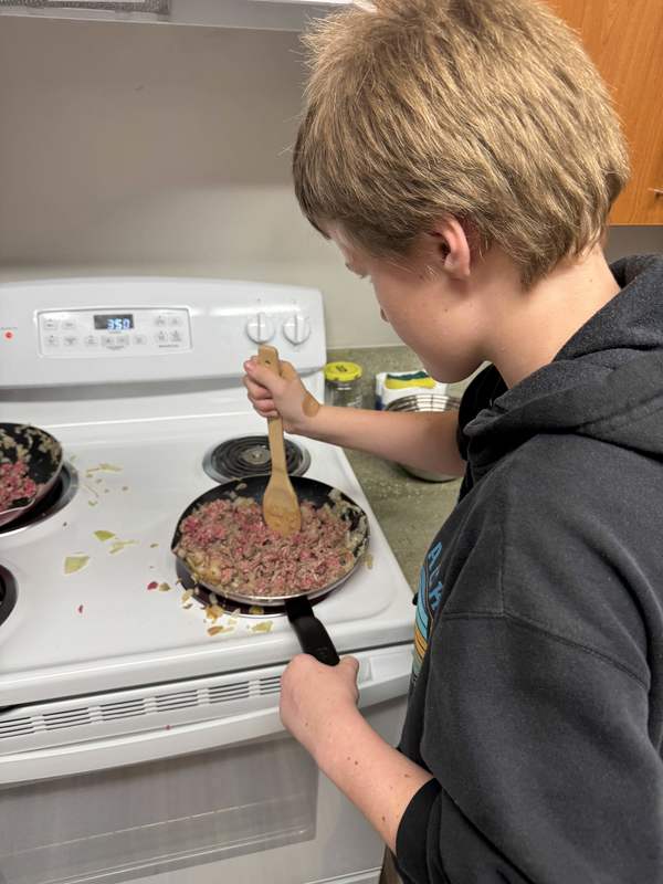 Student cooking ground beef.