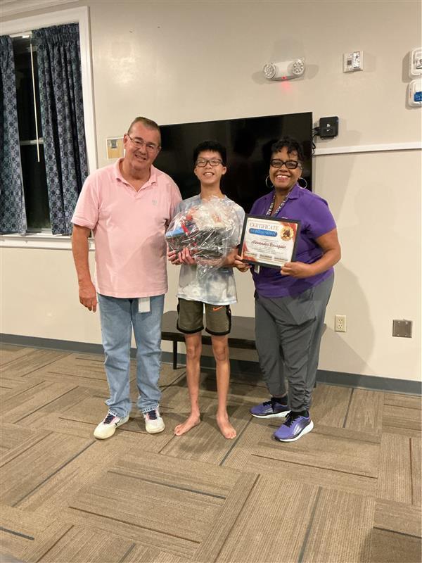 Alex receiving a certificate from two Residential Instructors.