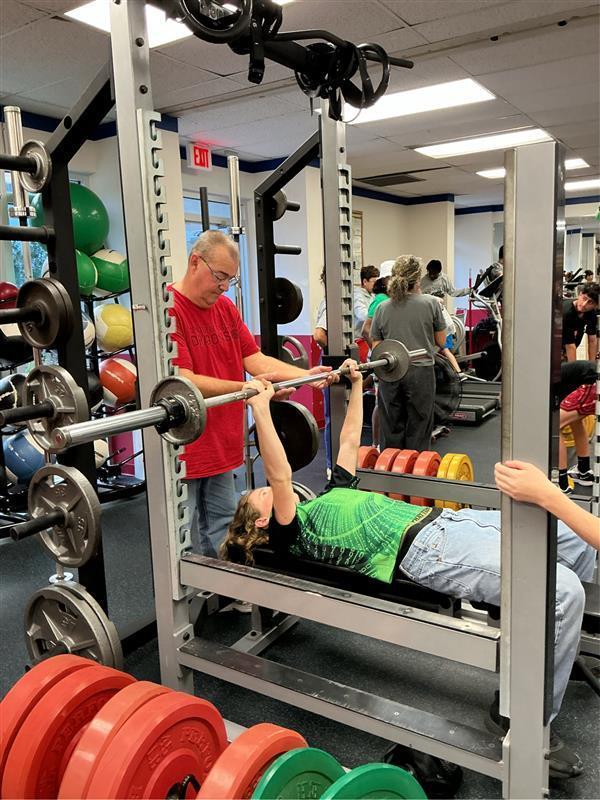Student working on bench press in the weight room.