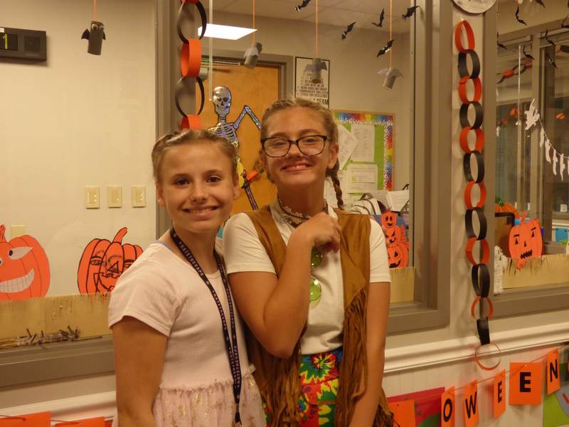 Two girls smiling with Halloween decorations behind them.