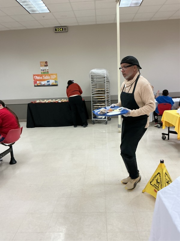 Staff member carrying a tray of food.
