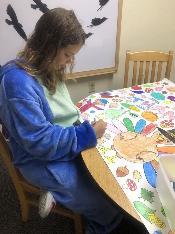 Student coloring on a Thanksgiving Day banner.