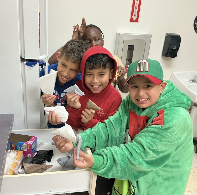 Boys folding plastic bags into triangles.