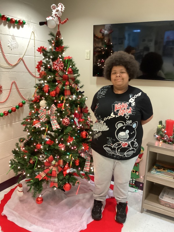 Girl standing in front of Christmas tree.