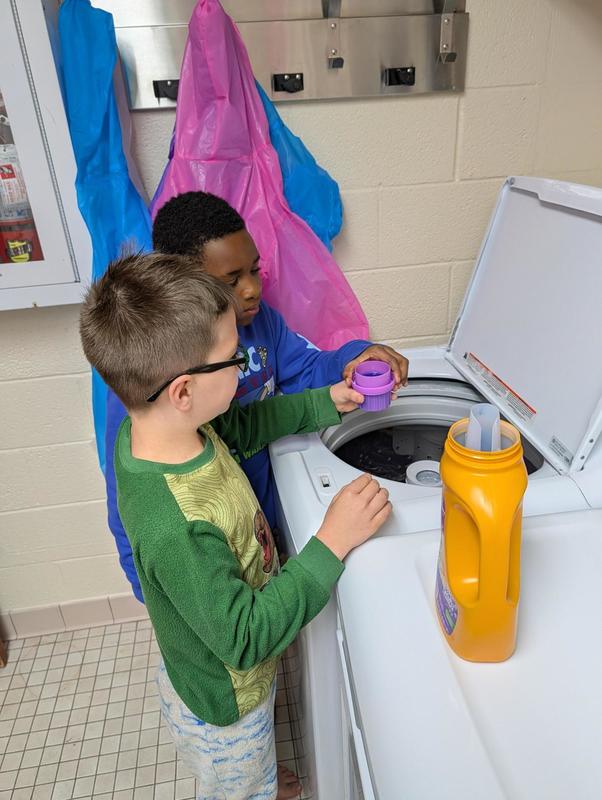 Two boy students learning to do laundry