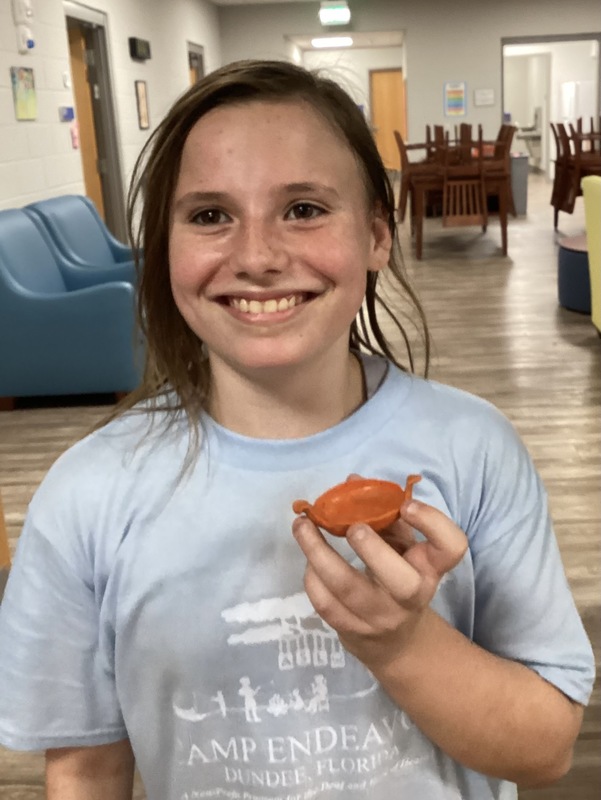 Middle school student smiling and holding clay project 