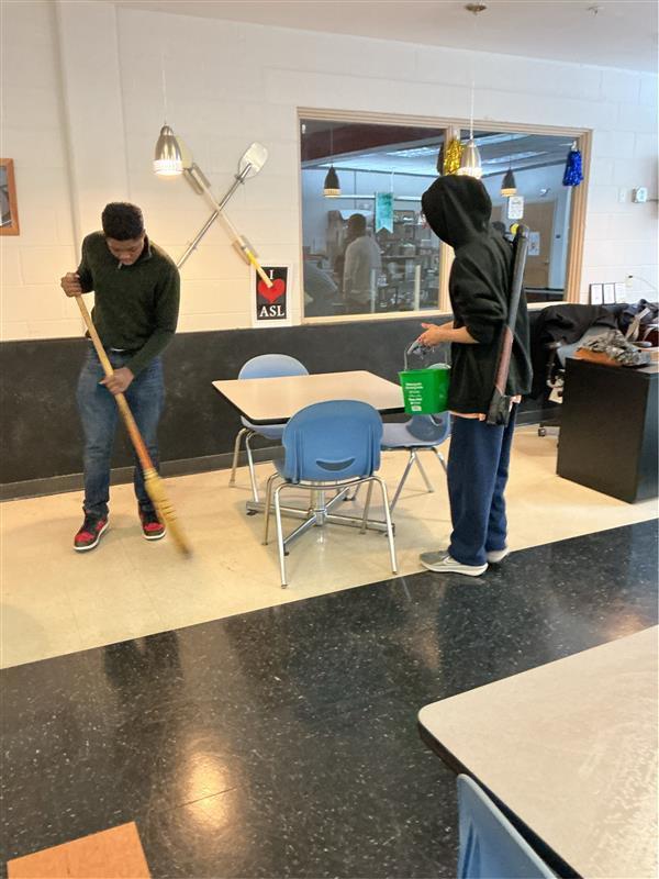 Two students cleaning and sweeping 