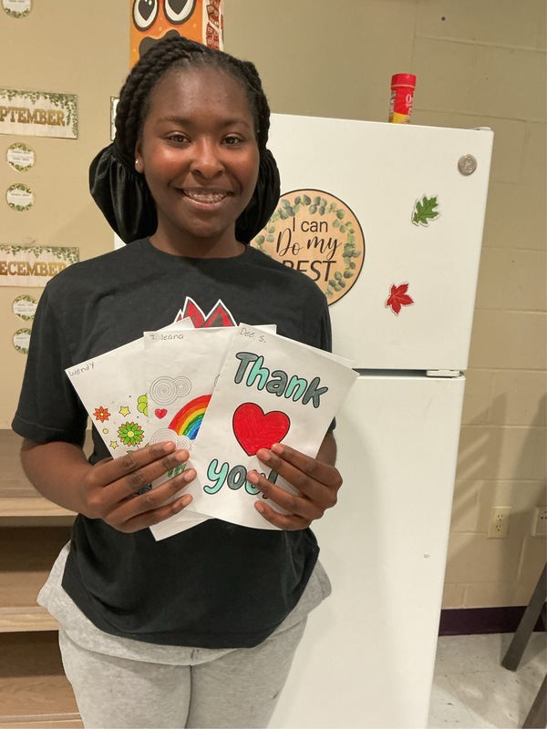 Student holding up 'Thank You' cards and smiling