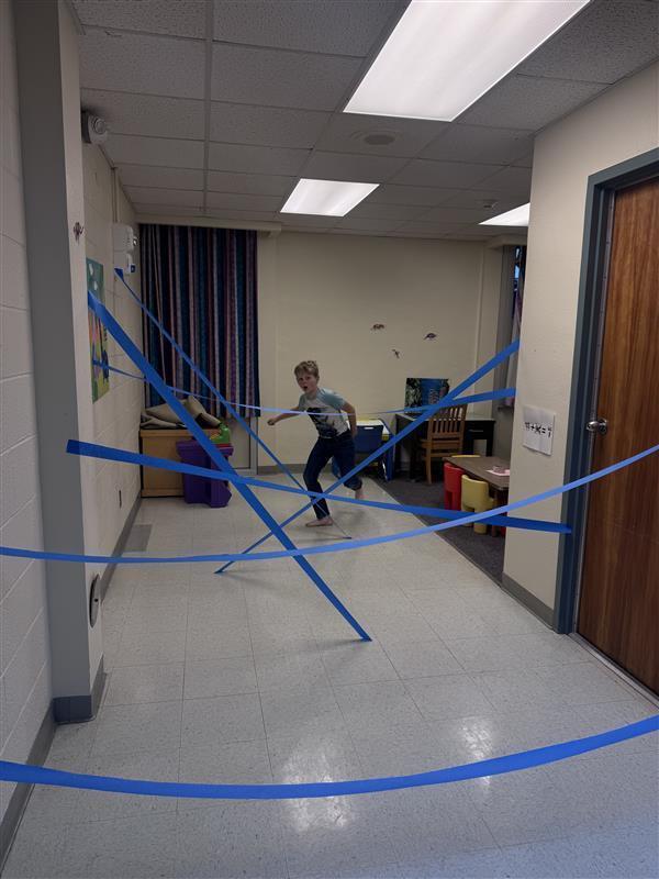 DES Student playing laser tag with blue tape in hallway