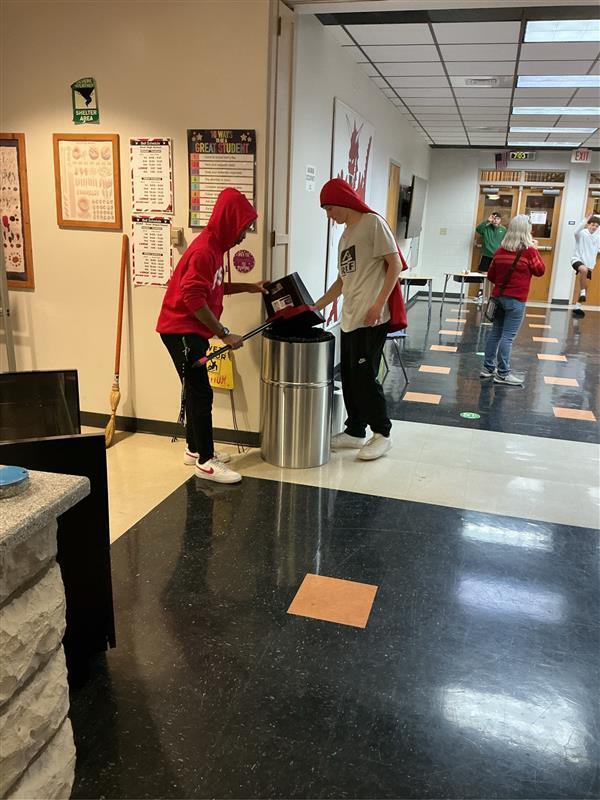 Two boys emptying trash in the Dragon's Lair.