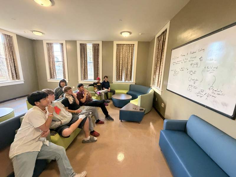Boys looking at a whiteboard and learning about Critical Thinking Skills.