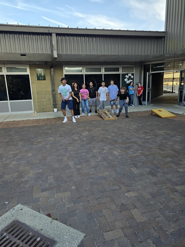 Students playing corn hole outside a building at Nease High School