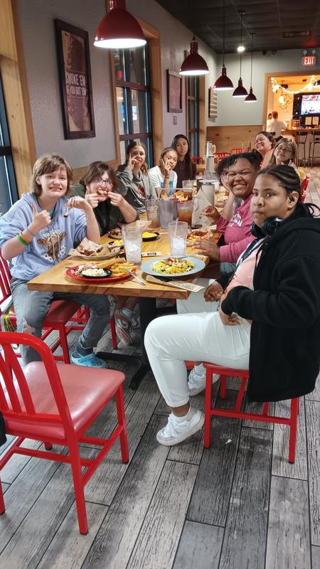 Girls sitting at restaurant, smiling at camera