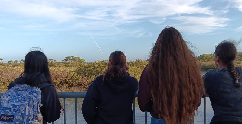 Four girls watching rocket launch outside