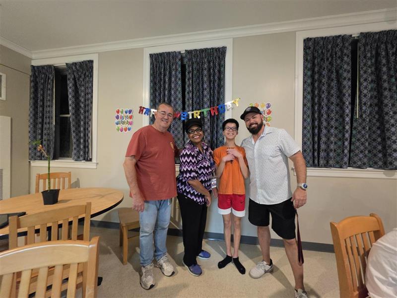 Student posing with staff in front of 'Happy Birthday' banner