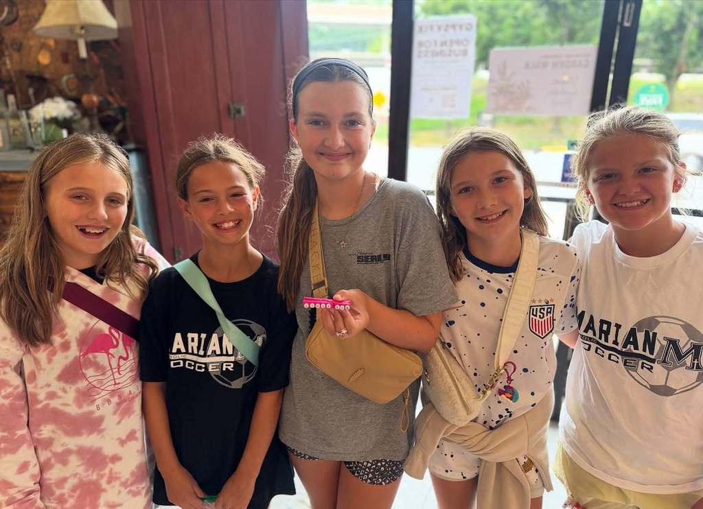 students holding a piece of hand crafted jewlery