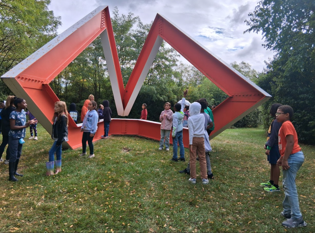 students posing near a large red sculpture