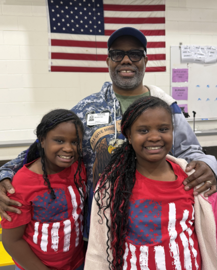 kids with their family who is a veteran. The girls are wearing american flag shirts. 