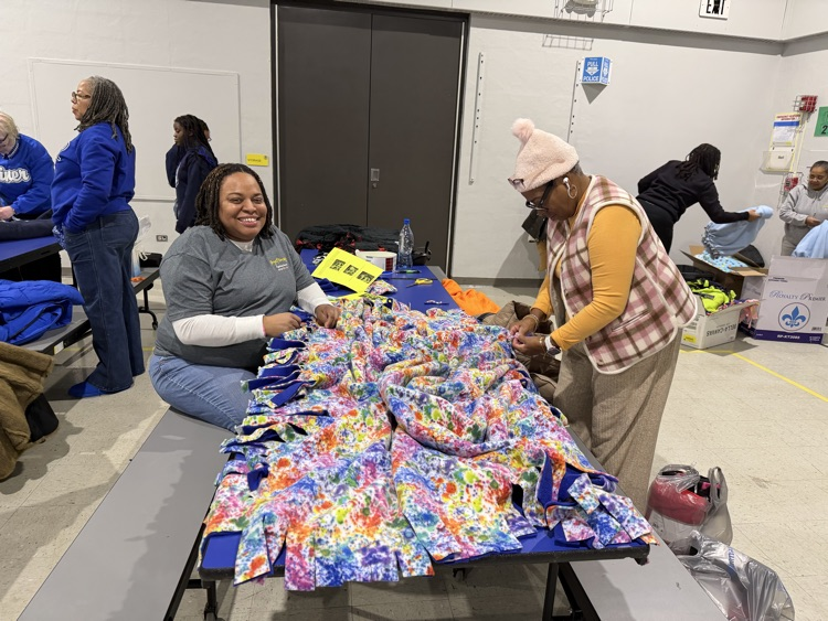 A teacher and a volunteer creating a blanket