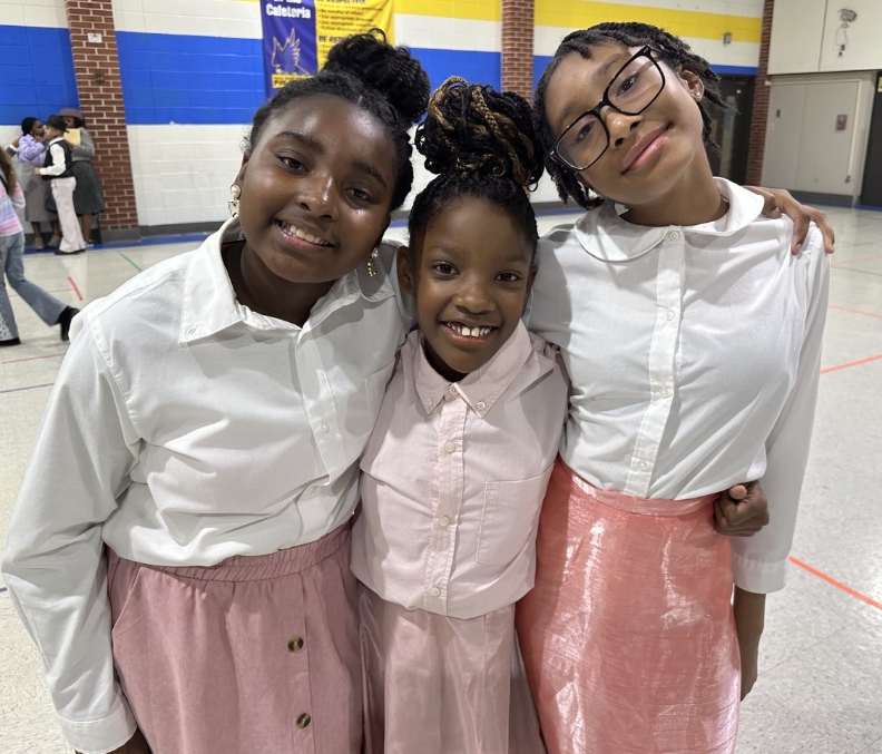 three girls standing and smiling.
