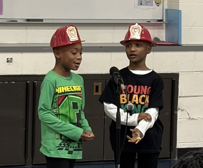 Two  kids talking into a microphone. 