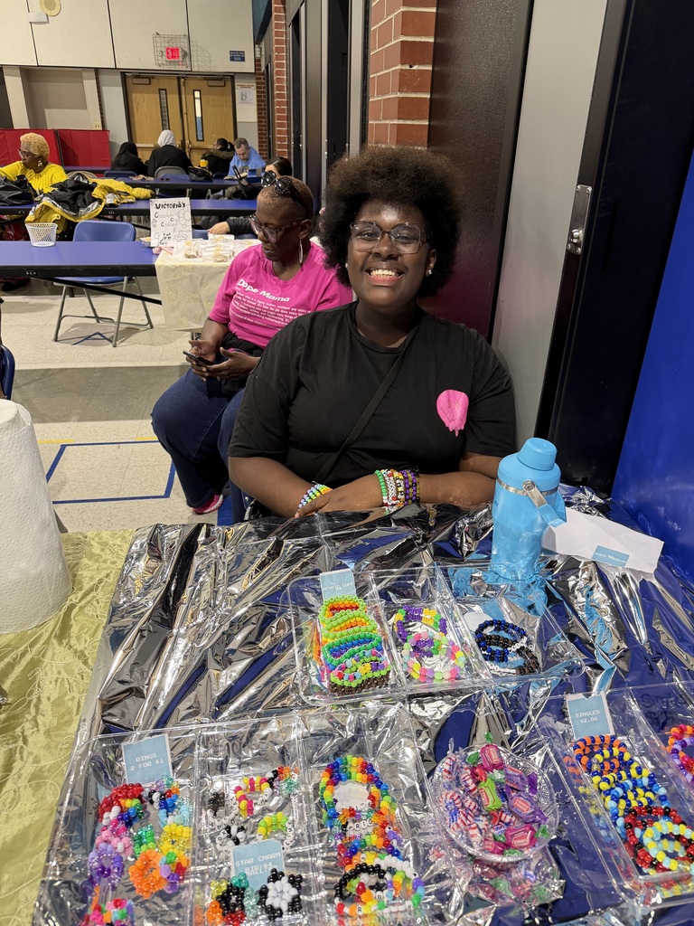 student in front of her bake sale items.