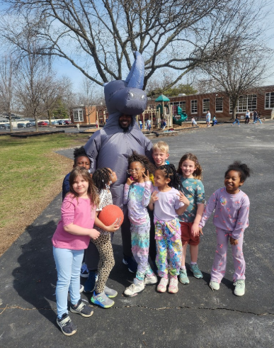 kids with the principal who is dressed in a silly costume. 