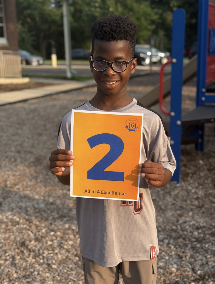 student holding a paper with the number 2. 