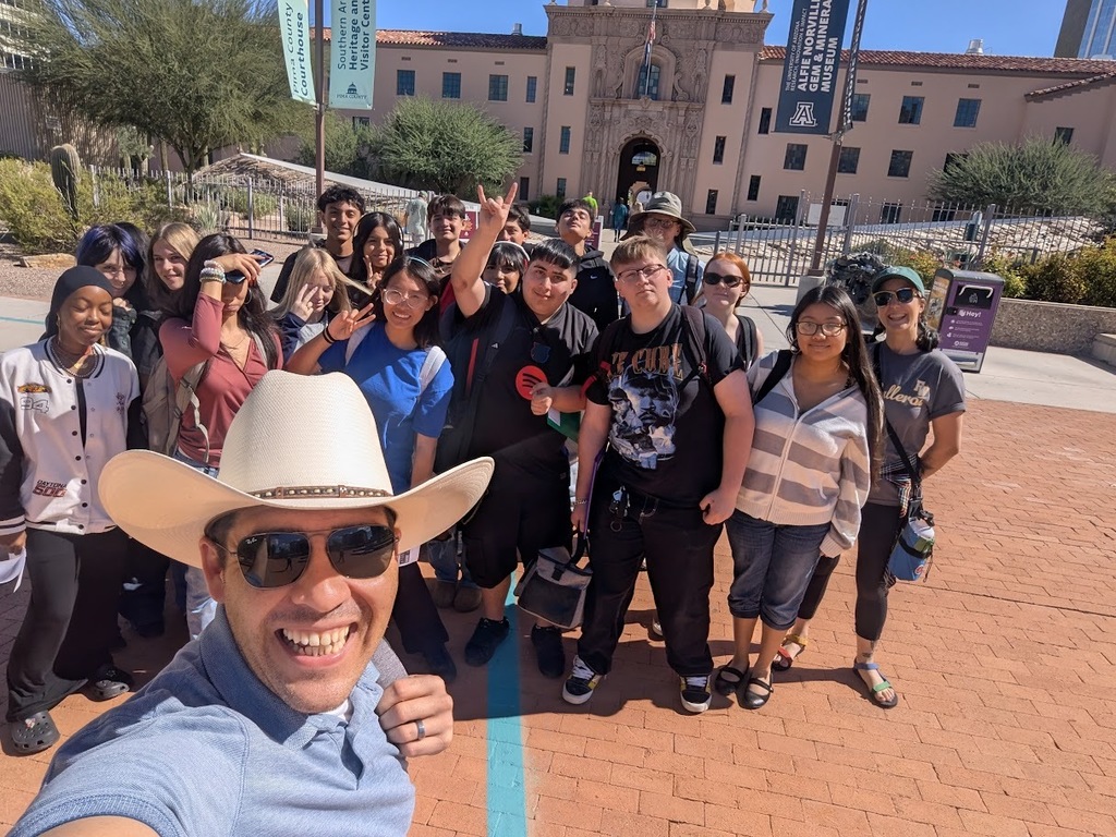 A group of Flowing Wells High School students and their teachers smile for a group photo during a sunny field trip to Tucson Meet Yourself in downtown Tucson, exploring cultural exhibits and performances as part of their AP Human Geography studies.