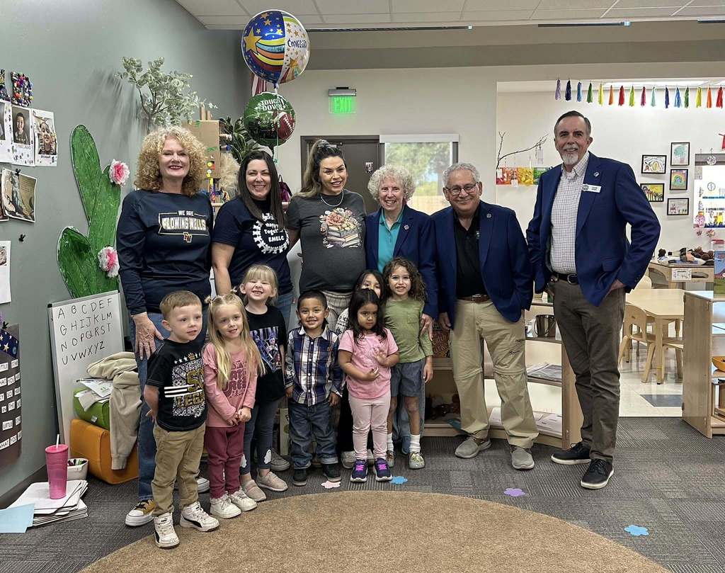A group of adults and preschool students stands together in a classroom at the Emily Meschter Early Learning Center to celebrate Jessica Jankowski Gallo’s Extra Yard for Teachers award. Balloons are displayed behind the group, and children are gathered at the front smiling for the photo.