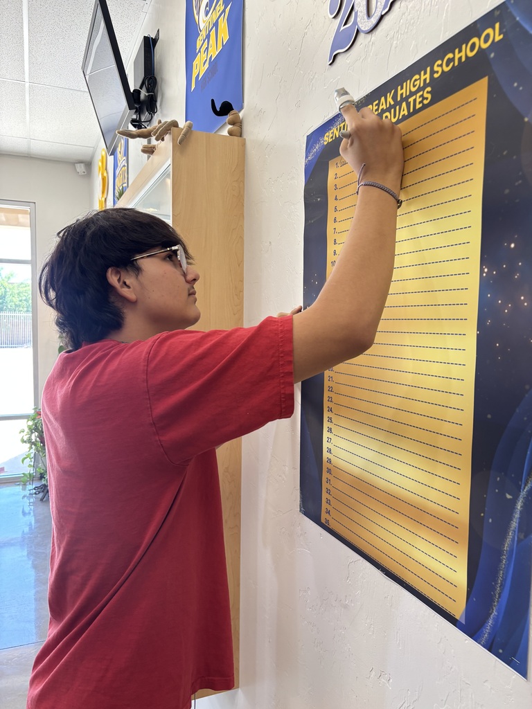 Student signs our poster of graduates as part of his last day celebration.