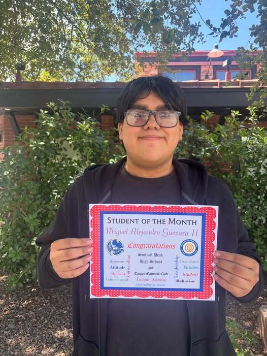 Proud student holding his Optimist Student of the Month certificate