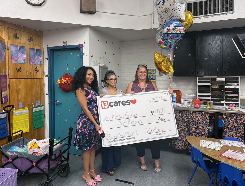 Kristi Gutierrez stands with two others holding a giant check.