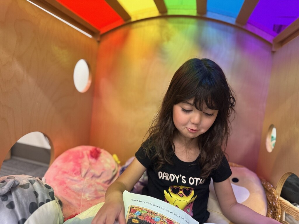 Student reading in rainbow cube. 