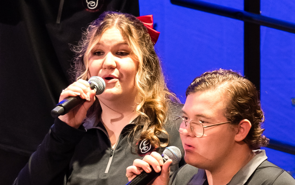 Two high school students are signing at a concert.
