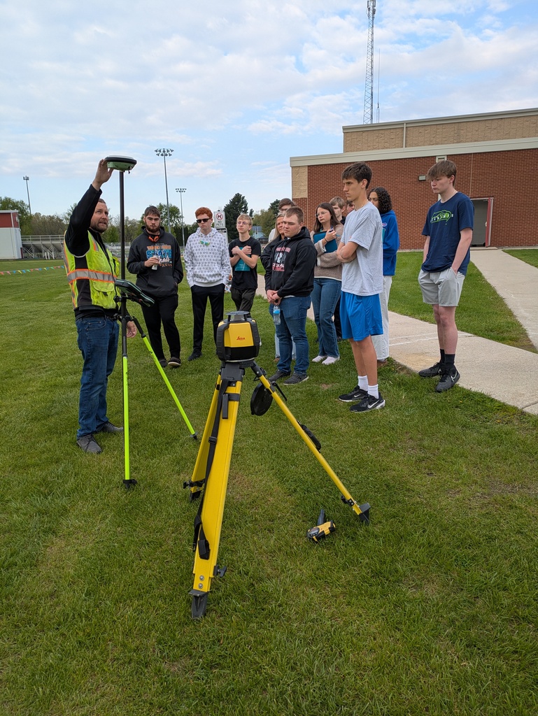 Engineer showing advanced surveying equipment to high school students. 