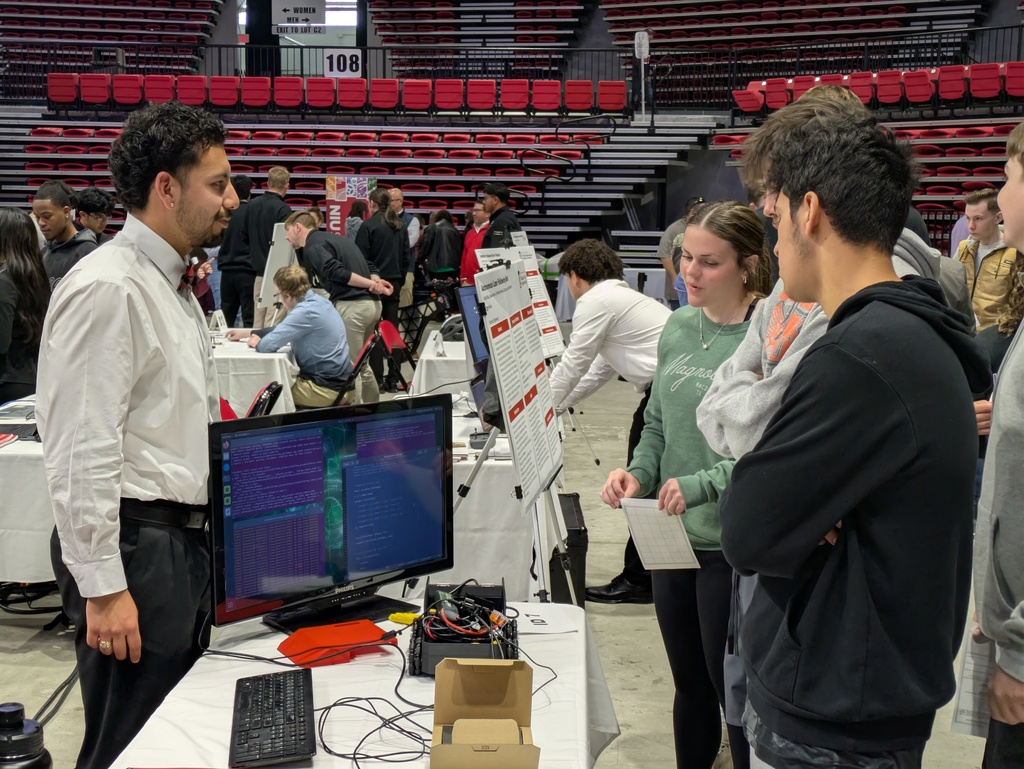 Engineer behind a display answering high school student questions. 
