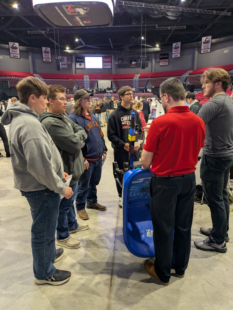 Three high school students watching a demonstration of an automated wheelbarrow. 
