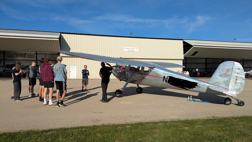 students looking at airplanes outside of the hanger