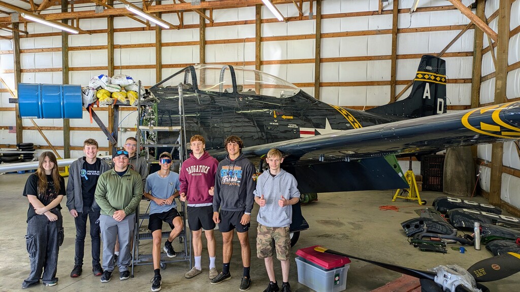 students looking at a T28 Trojan plane on the hanger without an engine 