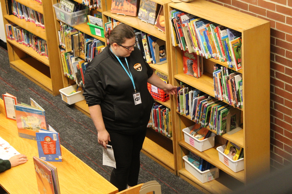 Student looking at books on a library shelf