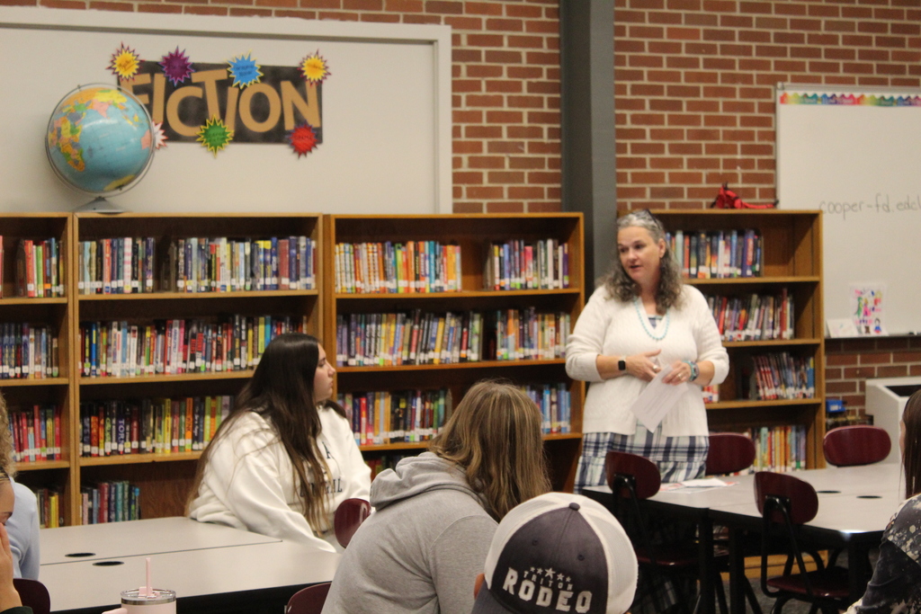 adult talking to students in a library