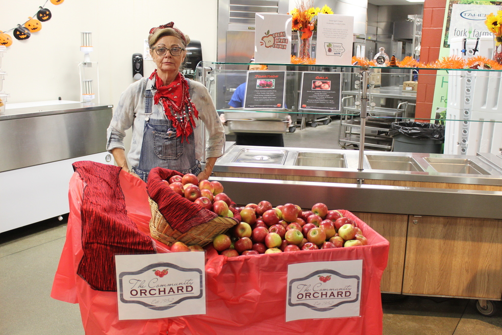 woman standing behind apples in a basket