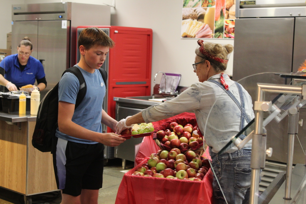 student receiving an apple at lunch