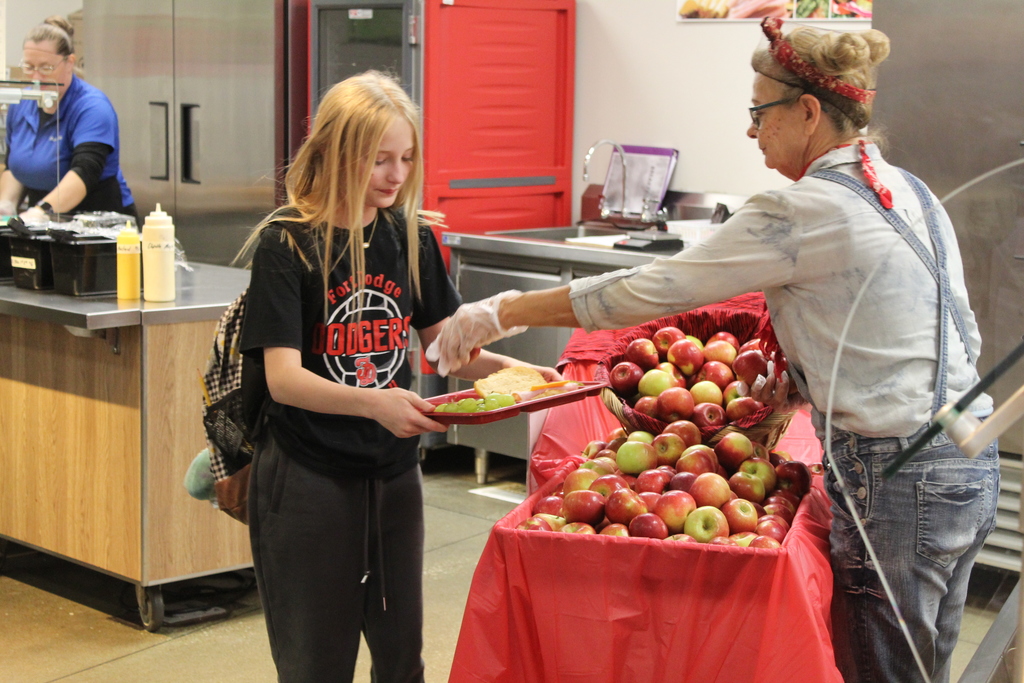 student receiving an apple at lunch